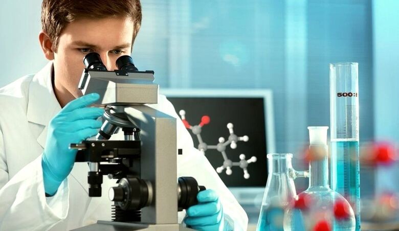 an expert examines material under a microscope